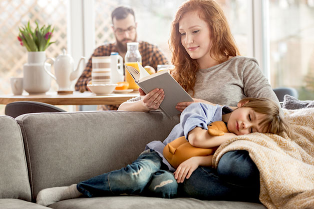 Man at a table, woman reading, child sleeping, all enjoying improved indoor air quality from their Infinity Air Purifier
