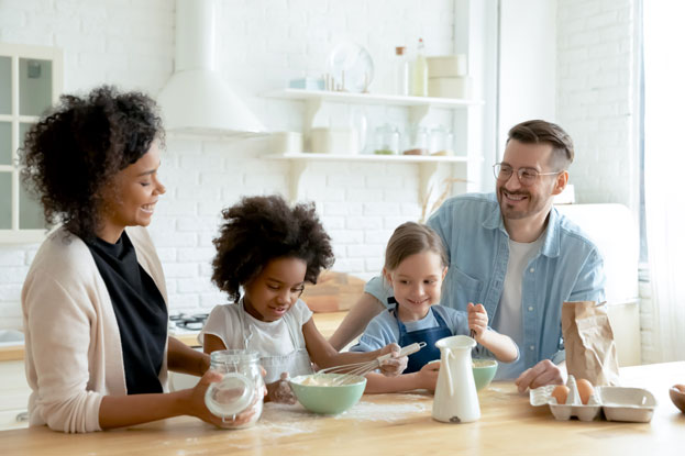 Two adults and two children baking together in their climate controlled kitchen