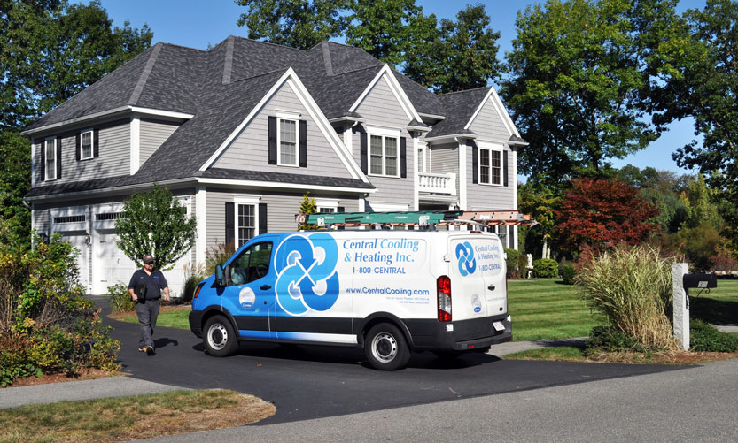 Central Cooling technician walking to his work van parked in the driveway of a priority service plan customer