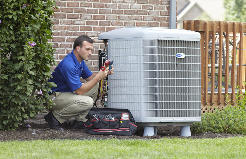 Central Cooling service technician outside working on a Carrier air conditioning compressor