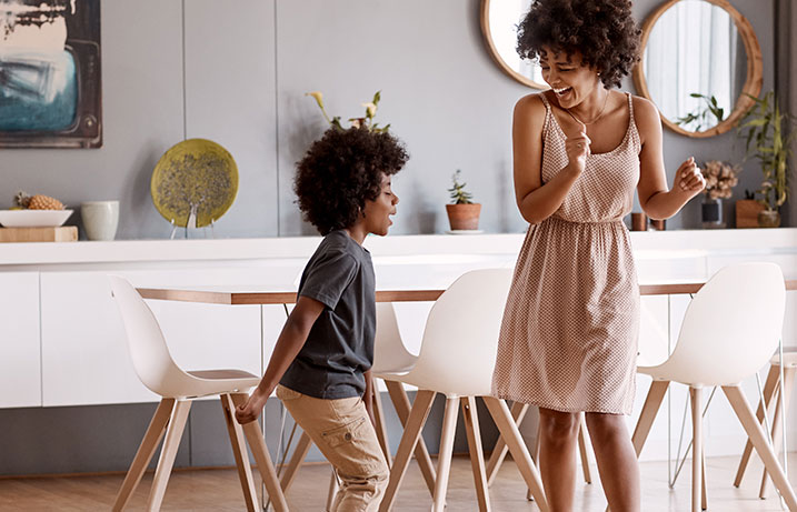 Happy woman and child dancing in the dining room enjoying purified air from their HVAC upgrade, Halo-LED