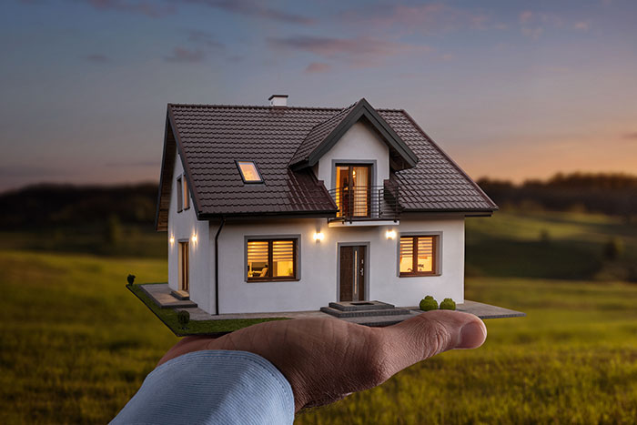 Man's hand holding a model home with a central heating a cooling system installed by Central