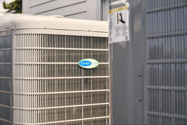 Close-up of two outdoor HVAC units next to a building, with the Carrier brand logo visible on one unit—perfect for showcasing professional ac installation results, and fixing common carrier AC problems by trusted experts Central Cooling.